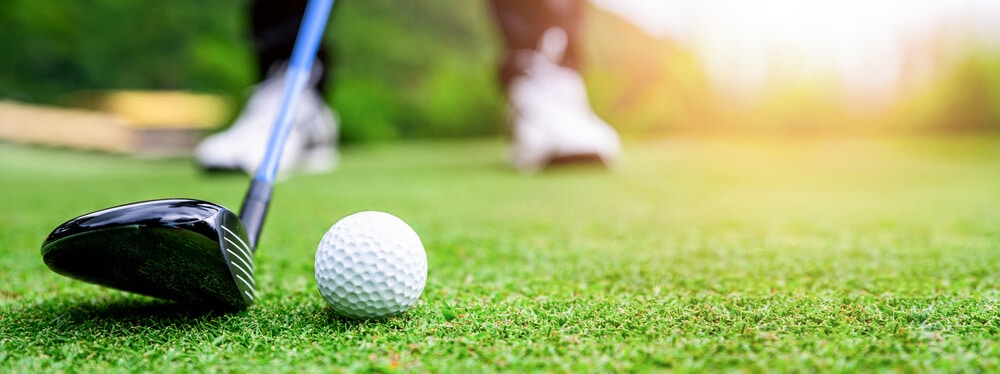 A golf club about to hit a golf ball, representing a popular live auction item